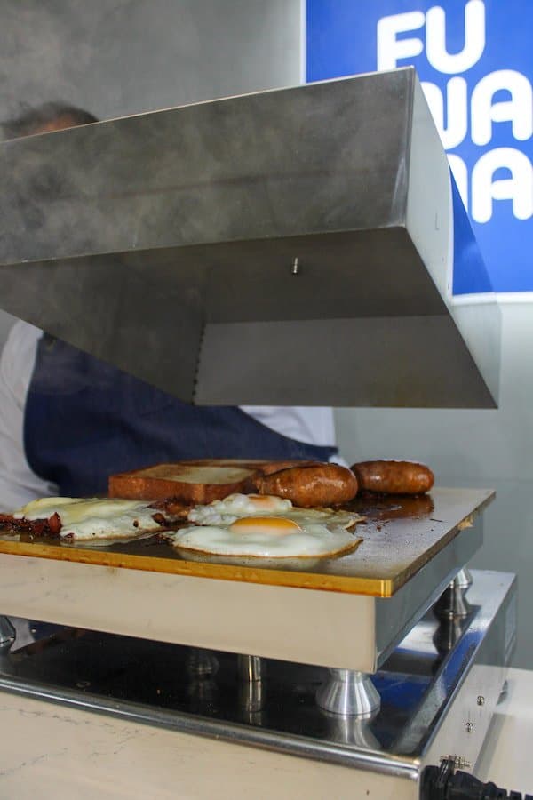 Fuwamai kitchen grill with fried eggs, sausages, and toast being prepared fresh in St Julians Malta